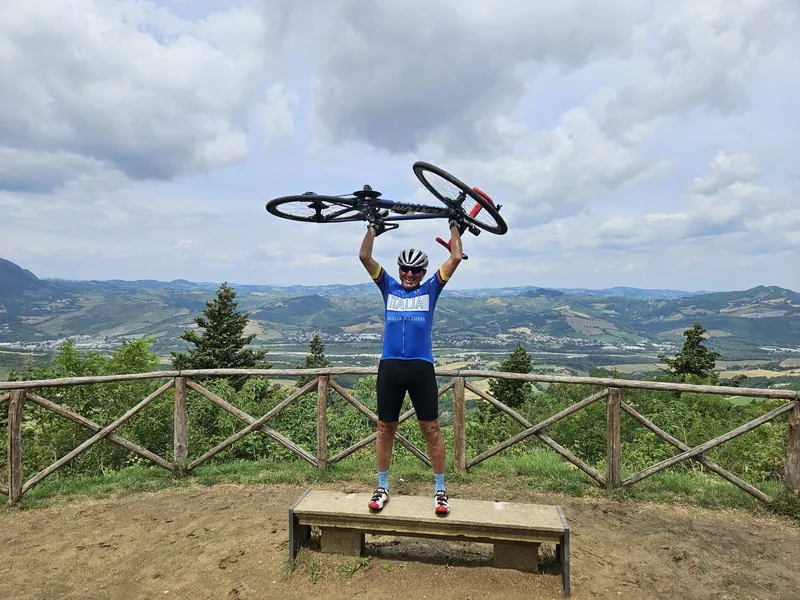 La bici alzata al cielo, in cima alla salita