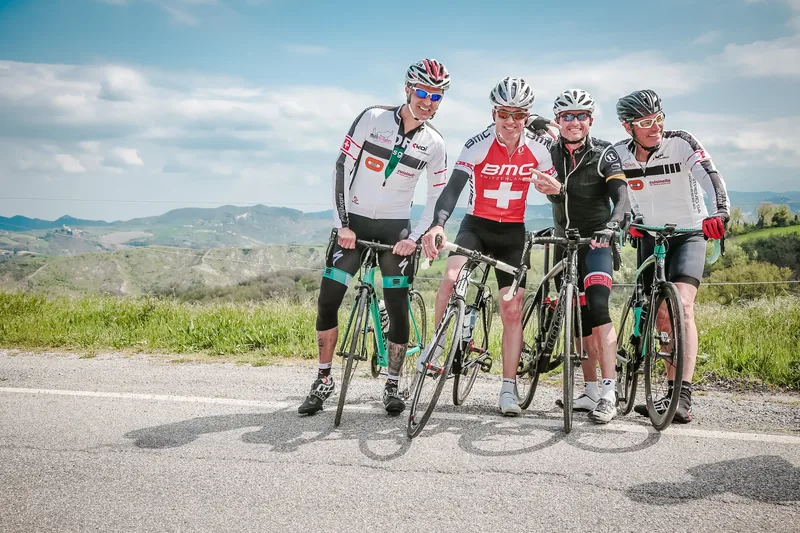Quattro ciclisti del gruppo Capuccino sorridenti sulle colline