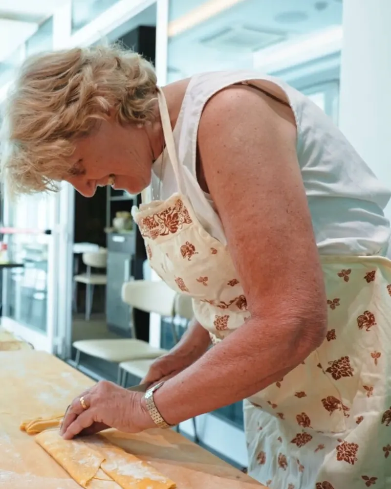 La sfoglina tira la pasta a mano durante la scuola di cucina