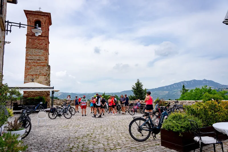 Ciclisti in sosta ad Albereto, accanto alla torre del borgo